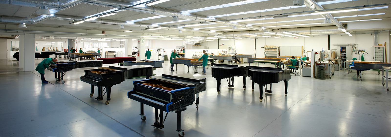 Interior de la fábrica de Fazioli con varios pianos de cola en producción